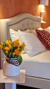 a vase of yellow flowers on a table next to a bed at Corte degli OstiNati in Variano