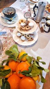 a table with plates of oranges and donuts on it at Corte degli OstiNati in Variano