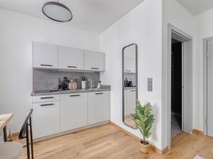 uma cozinha branca com armários brancos e um espelho em limehome Villach Gerbergasse em Villach