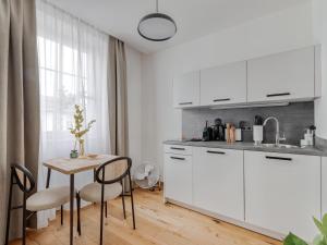 kuchnia z białymi szafkami, stołem i krzesłami w obiekcie limehome Villach Gerbergasse w Villach