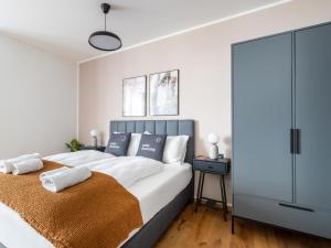 een slaapkamer met een groot wit bed met blauwe accenten bij limehome Villach Gerbergasse in Villach