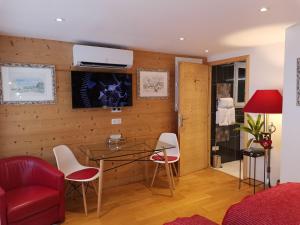 een woonkamer met een rode bank en een tafel en stoelen bij Chalet la Cachette Cyclists & Skiers in Le Bourg-dʼOisans