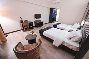 a hotel room with two beds and a chair at PRIME CITY HOTEL KLUANG in Kluang