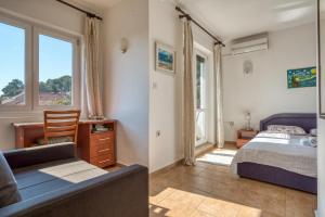 a bedroom with a bed and a couch and a window at Apartmani Olga in Petrovac na Moru