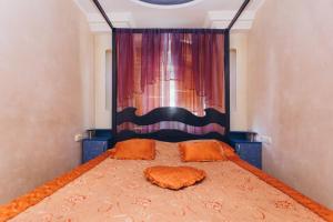 ein Bett mit orangefarbenen Kissen und ein Fenster im Schlafzimmer in der Unterkunft Перекопская центр люкс квартира посуточно почасово in Sumy