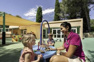 a woman and two children playing in a playground at Belambra Clubs Le Pradet - Lou Pigno in Le Pradet