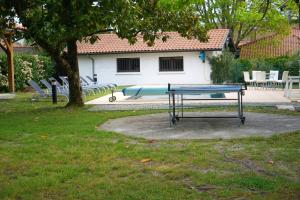 una mesa de ping pong en un parque junto a un árbol en Villa de 6 chambres avec piscine privee jardin clos et wifi a Sainte Eulalie en Born, en Sainte-Eulalie-en-Born