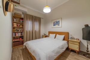 ein Schlafzimmer mit einem weißen Bett und einem Bücherregal in der Unterkunft Vintage-style Garden Apartment in Athen
