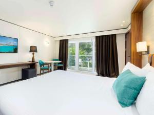 a hotel room with a large bed and a large window at Sonesta Maho Beach All Inclusive Resort Casino & Spa in Maho Reef