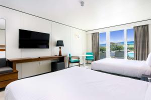 a hotel room with two beds and a television at Sonesta Maho Beach All Inclusive Resort Casino & Spa in Maho Reef