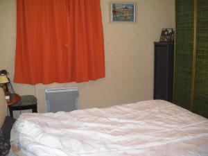 a bedroom with a bed and an orange curtain at grand appartement en résidence in Vendôme
