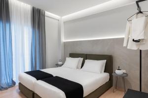 una camera da letto con un letto con lenzuola bianche e tende blu di Acropolis White Key Residence ad Atene