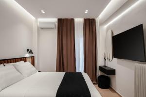 a hotel room with a bed and a flat screen tv at Acropolis White Key Residence in Athens