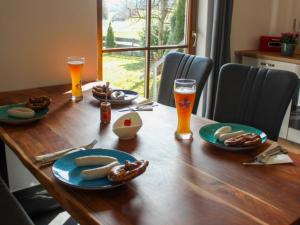 einen Holztisch mit Teller mit Speisen und zwei Gläsern Bier in der Unterkunft Landhaus GLÜCKSmoment in Rottau