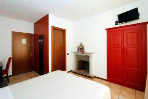 a bedroom with a red door and a fireplace at Albergo Maccagno in Maccagno Inferiore