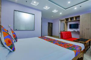 um quarto com uma cama grande e uma cadeira vermelha em FabHotel New Central em Bhubaneshwar