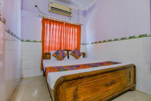 um quarto com uma cama de madeira e uma cortina laranja em FabHotel New Central em Bhubaneshwar