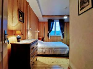 a bedroom with a bed with a dresser and a window at La Tirelire in Cosswiller