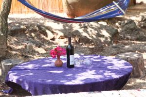 una mesa con una botella de vino y un jarrón de flores en Back to Nature Camping & Huts, en Mikhmannim