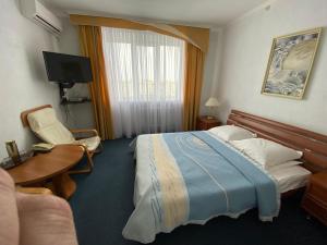 Habitación de hotel con cama, escritorio y TV. en Dnipro Hotel en Cherkasy