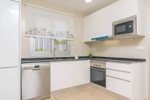 eine Küche mit weißen Schränken und einer Mikrowelle in der Unterkunft Villa Dolphin by Slow Villas in Sa Ràpita