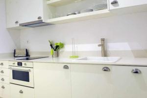 una cucina con armadi bianchi e lavandino di Modern Apartment a Barcellona