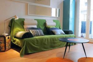 a green couch in a living room with a table at Calm Modern Apartment in Barcelona