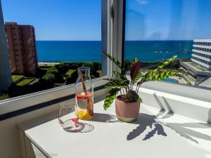 a table with two glasses and a plant and a window at PÓVOA BEACH OCEAN VIEW in Póvoa de Varzim