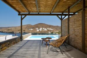 un patio con tavolo, sedie e piscina di Amal Kythnos Suites a Kithnos