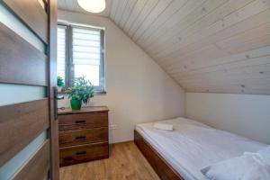 um quarto com uma cama, uma cómoda e uma janela em Domki Solina Róża Wiatrów em Solina