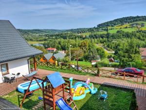 um quintal com uma área recreativa com cadeiras e um parque infantil em Domki Solina Róża Wiatrów em Solina