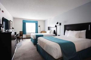 a hotel room with two beds and a desk at Ramada by Wyndham Surrey/Langley in Surrey