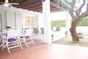 un porche con sillas blancas, una mesa y un árbol en Cozy marine & spa villa, en Cambrils