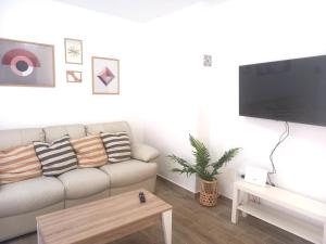 a living room with a couch and a flat screen tv at Los Barqueros 25 by Best Holidays Fuerteventura in Corralejo