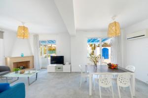 uma sala de estar branca com uma mesa e cadeiras em Fig Tree Bay Villa 3 em Protaras