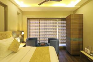 a bedroom with a bed and chairs and a window at Hotel The IVY Grand With Free Secured Parking in New Delhi
