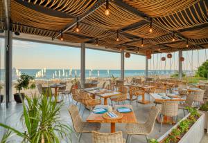 a restaurant with tables and chairs and a view of the ocean at GRIFID Encanto Beach Hotel - MediSPA, Ultra All Inclusive & Private Beach in Golden Sands