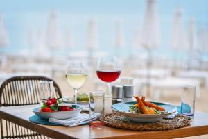 a table with a plate of food and two glasses of wine at GRIFID Encanto Beach Hotel - MediSPA, Ultra All Inclusive & Private Beach in Golden Sands