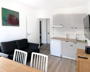 ein Wohnzimmer mit einem schwarzen Sofa und einer Küche in der Unterkunft Office Apartment zentral zur Dortmunder Innenstadt in Dortmund