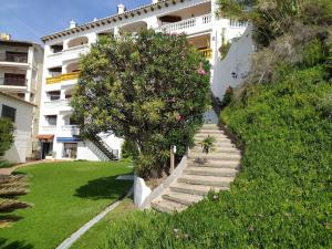 een trap naar een gebouw met een boom bij Little Paradise . Apartment in front of the sea in Comarruga