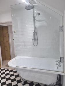 a white bath tub in a bathroom with a shower at Cosy Cottage, in the idyllic town of Holt in Holt