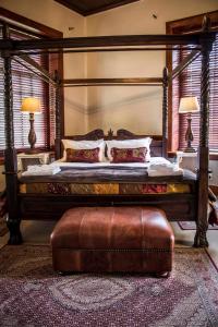 a bedroom with a canopy bed with a brown ottoman at Kralinbergh Estate Guesthouse in Ermelo