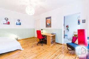um quarto com uma secretária e uma cama com cadeiras vermelhas em Sunny Studio at Wismarplatz em Berlim