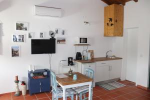 a kitchen with a table and a tv on the wall at Casa do Alambique in Tomar