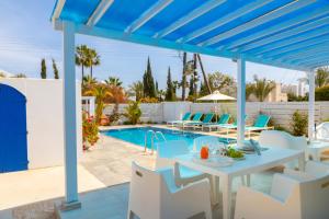 a patio with a table and chairs next to a swimming pool at Fig Tree Bay Villa 4 in Protaras +70 photos