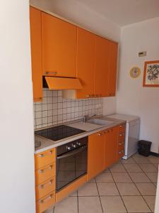 La cuisine est équipée d'armoires orange et d'un four avec plaques de cuisson. dans l'établissement Maia Incantevole, à Levanto