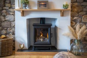a fireplace in a living room with a stone wall at Elidyr Cottage - 3 Bedroom Cottage - Amroth in Amroth