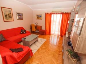 een woonkamer met een rode bank en een tafel bij Apartmani Abesinac in Makarska