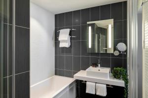 La salle de bains est pourvue d'un lavabo, d'une baignoire et d'un miroir. dans l'établissement COVE Centrum, à La Haye