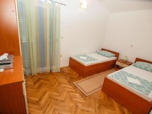een kamer met 2 bedden en een houten vloer bij Apartmani Abesinac in Makarska